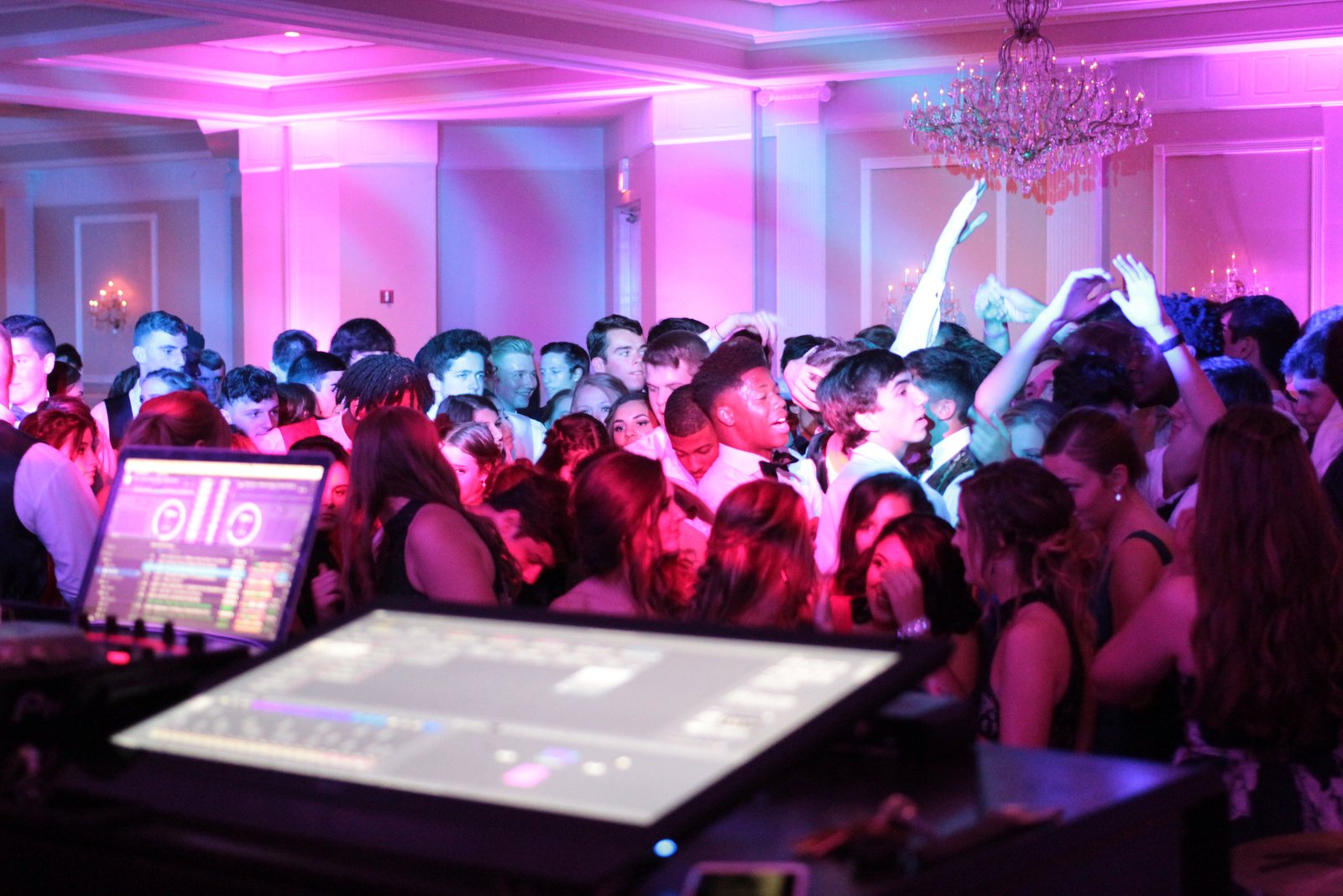 Hands up on a full dance floor under uplighting